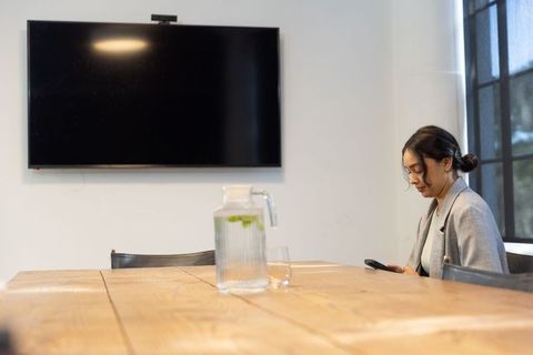 Businesswoman at Conference Table with Smartphone and Refreshments