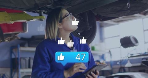 Female mechanic using tablet in auto repair shop with engagement icons