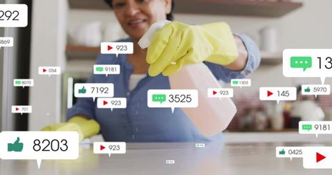Indian woman cleaning kitchen countertop in yellow gloves spraying with social media notifications
