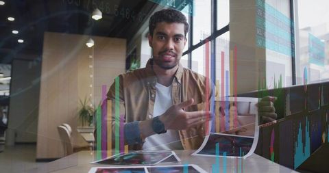 Young analyst presenting printed charts with data visualization overlays in workspace