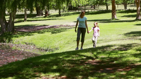 Mother Walking with Daughter in Sunny Park