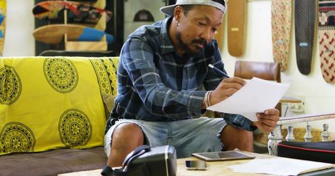 Thoughtful man reviewing documents in casual room with cultural decor