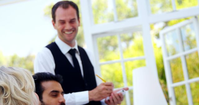 Smiling Waiter Taking Orders in Bright Restaurant - Download Free Stock Images Pikwizard.com