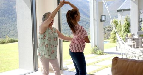 Grandmother and granddaughter dancing joyfully in bright living room