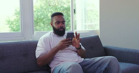 Relaxed Man Engaging with Mobile Technology on Comforting Sofa