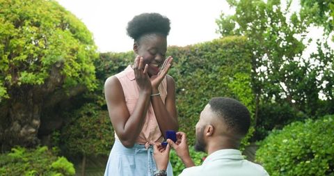 Romantic proposal in vibrant garden setting evokes joyous surprise