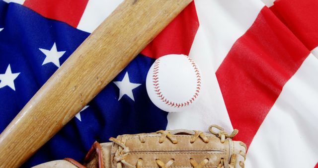 Close-up of baseball sports equipment arranged on an American flag symbolizing America's pastime. Ideal for use in sports-related articles, patriotic-themed advertising, and design projects conveying a blend of sports and national pride.
