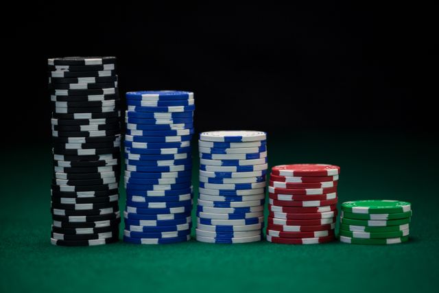 Stacked casino chips in various colors arranged on a green poker table. Ideal for use in articles about gambling, casino games, poker strategies, or casino-themed events. Perfect for illustrating high-stakes gaming or betting scenarios.