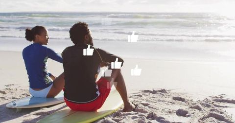 Couple relaxing post surf with virtual thumbs-up on beach
