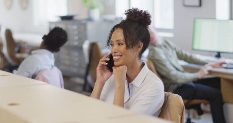 Cheerful Businesswoman Talking on Smartphone in Creative Office