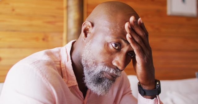 Senior african american man spending time in log cabin touching his head. Log cabin and lifestyle concept.