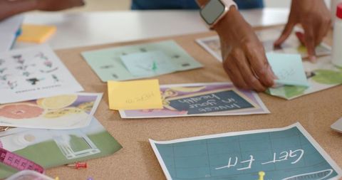 Creative team brainstorming with sticky notes and moodboard on cork table for wellness