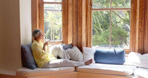 Relaxed Senior Woman Enjoying Tea in Sunlit Window Nook