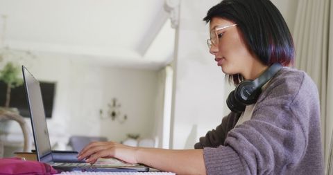 Teen Student Typing on Laptop While Wearing Headphones