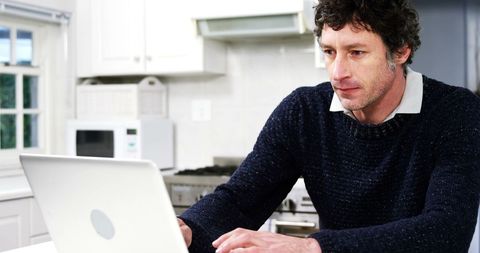 Focused Man Using Laptop in Modern Kitchen Interior