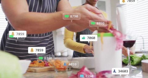 Couple grating vegetables at bright kitchen sink with wine and floating social media alerts