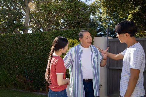 Multigenerational family connecting in sunlit backyard garden