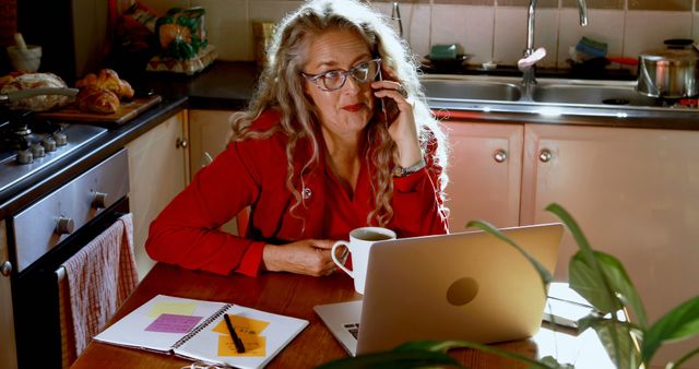 Mature Woman Working from Home in Kitchen while on Phone - Download Free Stock Images Pikwizard.com