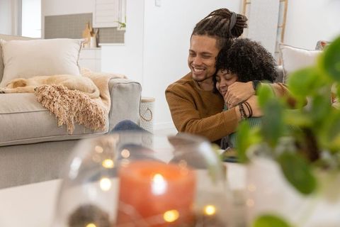 African american couple embracing on cozy living room floor with dog and candlelight