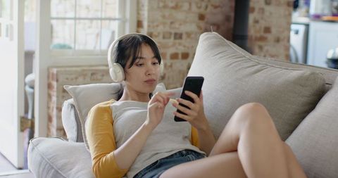 Young Woman Enjoying Music While Online Shopping at Home
