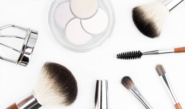 Assorted makeup brushes and tools, including different types of brushes, makeup palette, and eyelash curler, on a white background. Ideal for beauty blogs, cosmetic product advertisements, makeup tutorial visuals, and websites featuring beauty tips.