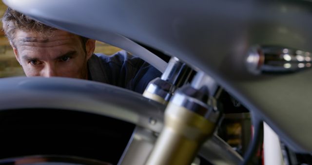 Mechanic Inspecting Motorcycle Closely with Focused Expression - Download Free Stock Images Pikwizard.com