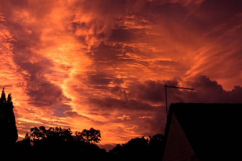 Sunset sky with dramatic red and orange clouds silhouetting rural landscape