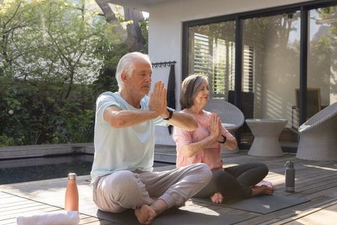 Senior Couple Practicing Outdoor Yoga by Pool for Wellness