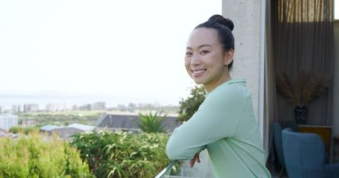 Asian Woman Enjoying Urban Skyline from Modern Balcony