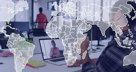Holding phone while joining laptop video call in open-plan office with world map overlay