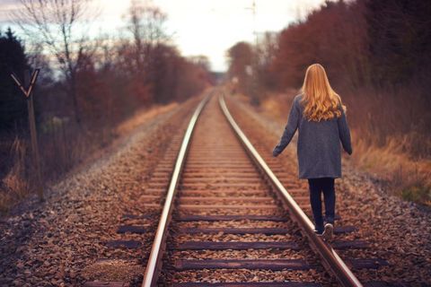 Woman Walking on Railroad Track in Tranquil Setting