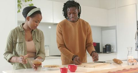 African american couple preparing homemade pie together in bright modern kitchen