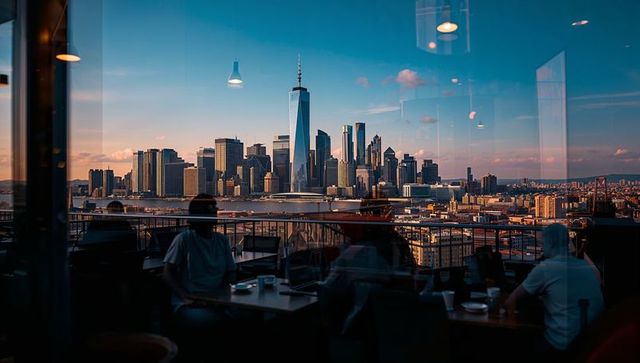 Rooftop diners enjoying manhattan skyline with one world trade center at golden hour
