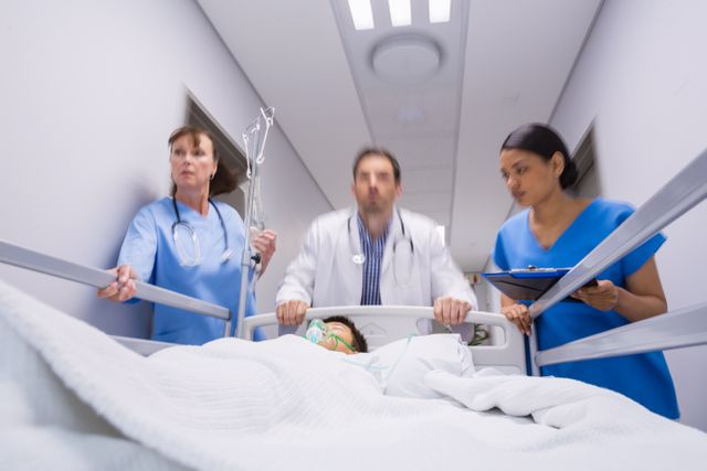 Doctors pushing emergency stretcher bed in corridor at hospital