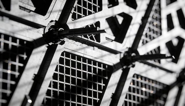 Darts striking steel-tipped gridded board casting dramatic shadows on hexagonal metal