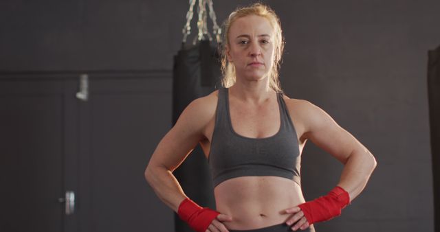 Portrait of caucasian female boxer with hands on hips standing at the gym. sports, training and fitness concept