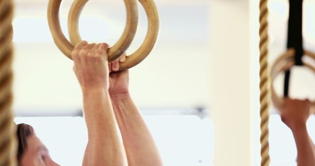 Person gripping gymnastic rings with strong hands, depicting dedication to fitness and training. Ideal for use in blogs or articles on fitness routines, gym training, or motivation for athletes. Suitable for advertising gym memberships, fitness equipment, or personal training services.