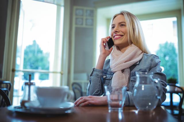 Smiling woman talking on mobile phone in cafÃ©