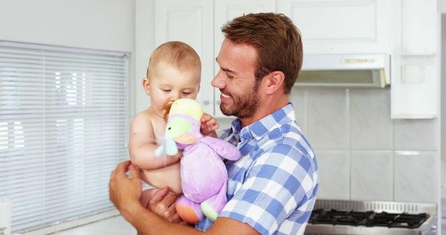 Smiling Father Holding Baby with Plush Toy in Kitchen - Download Free Stock Images Pikwizard.com