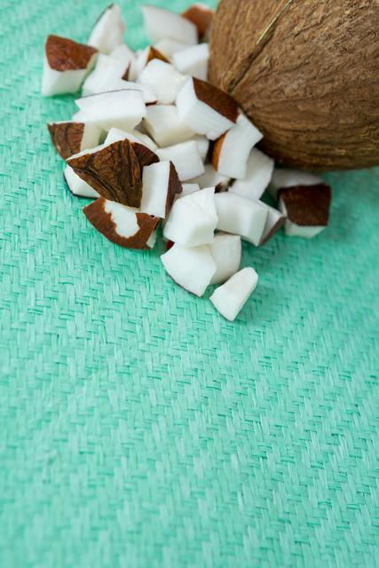 Close-up of coconut and coconut pieces on green cloth. Ideal for use in food blogs, healthy eating articles, tropical fruit promotions, organic food advertisements, and natural product packaging designs.