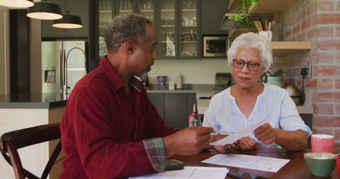 Serious Senior Couple Discussing Finances at Kitchen Table