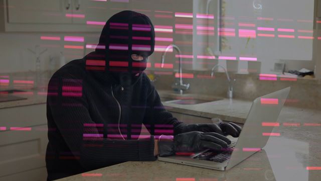 A person wearing a balaclava and gloves uses a laptop in a kitchen setting, suggesting themes of cybercrime and online data theft. Overlay of digital data patterns highlights the focus on technology and security breaches. Ideal for illustrating cybersecurity threats, digital privacy concerns, or articles on hacking trends. Helps in evoking a sense of urgency and caution in technology contexts.