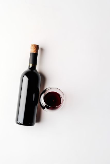 Wine bottle and glass with red wine on white background, created using generative ai technology. Wine week, drink, alcohol and wine tasting awareness concept digitally generated image.