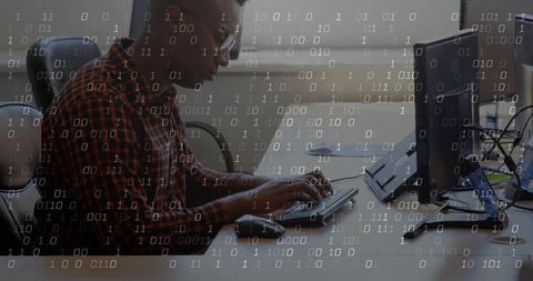 Coding developer leaning forward at modern workstation with floating binary overlay