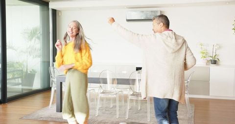 Senior Couple Joyfully Dancing in Modern Dining Room