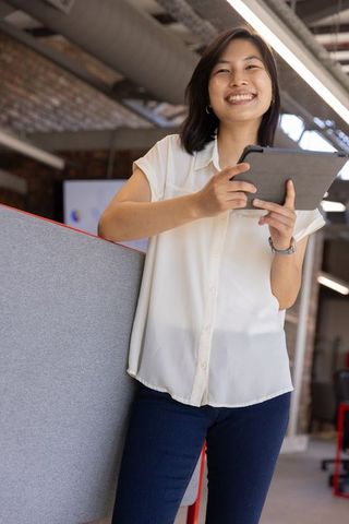 Smiling Businesswoman Using Tablet in Open-Plan Office Workspace