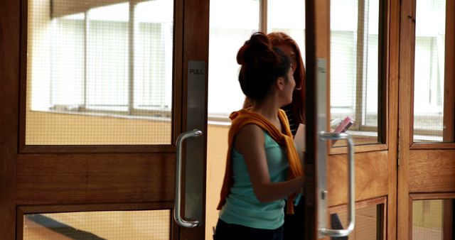 Two Women Entering Modern Building through Wooden Doors - Download Free Stock Images Pikwizard.com