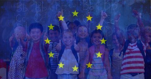 Diverse group of happy schoolchildren holding thumbs up in classroom