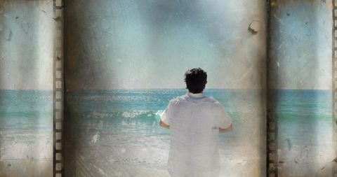 Standing man facing turquoise sea in white shirt with vintage filmstrip beach horizon