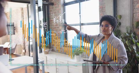 Professional woman analyzing data on glass board using tablet